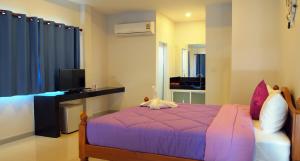 sypialnia z fioletowym łóżkiem i biurkiem w obiekcie KP Mountain Beach w mieście Pran Buri