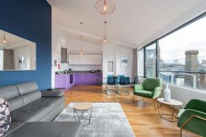 ein Wohnzimmer mit einem Sofa und Stühlen sowie eine Küche in der Unterkunft Mulberry South Penthouse by City Living London in London
