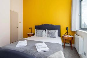 a bedroom with yellow walls and a bed with towels on it at Mulberry South Penthouse by City Living London in London