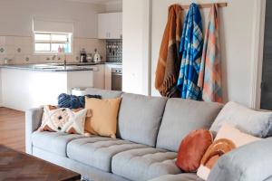 ein Wohnzimmer mit einer grauen Couch mit Kissen darauf in der Unterkunft The Hangout KING BEDS Hammock Chairs with a View in Port Campbell