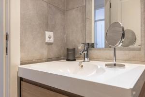 een badkamer met een witte wastafel en een spiegel bij Alfama 2BDR Duplex Apartment W/ Balcony by LovelyStay in Lissabon