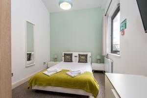 um quarto com uma cama com um cobertor amarelo em Mulberry North Penthouse by City Living London em Londres