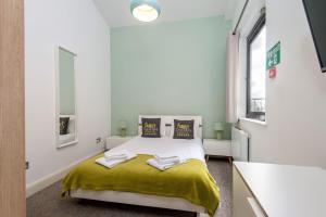 a bedroom with a bed with a yellow blanket at Mulberry North Penthouse by City Living London in London