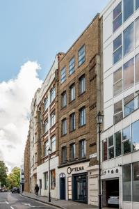 um edifício de tijolos numa rua com uma pessoa a passar por ele em Mulberry North Penthouse by City Living London em Londres