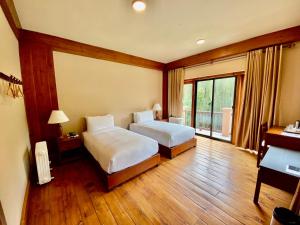a hotel room with two beds and a balcony at Taktsang Village Resort in Paro