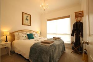 1 dormitorio con 1 cama con lámpara de araña y ventana en Bridgecroft Villa - French Provincial in Richmond with spa, en Richmond