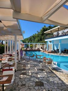 a pool at a resort with tables and chairs at Lido Corfu Sun Hotel 4 Stars All-inclusive in Benitses