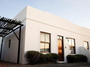 a white building with a red door and windows at De Hoek Selfsorg Eenhede in Beaufort West