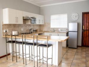 a kitchen with white cabinets and a island with bar stools at De Hoek Selfsorg Eenhede in Beaufort West