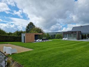 a large yard with white chairs and a building at Le Lièvre Debout Francorchamps - spa et sauna in Francorchamps