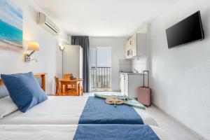 ein Hotelzimmer mit einem Bett und einem TV an der Wand in der Unterkunft Vibra Calima Apartamentos - Adults only in Sant Antoni de Portmany