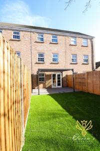 a large brick building with a fence and a yard at Cheerful Queens Quarters Boutique Rooms in Hartford