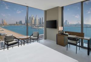a bedroom with a bed and a desk and chairs at Radisson Beach Resort Palm Jumeirah in Dubai