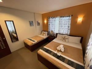 a hotel room with two beds and a window at Casa Coron Hotel in Coron