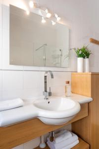 Baño blanco con lavabo y espejo en Asunción Suite Apartment, en Sevilla