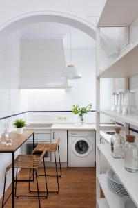 eine weiße Küche mit einem Tisch und einer Waschmaschine in der Unterkunft Magno Apartments Asunción in Sevilla