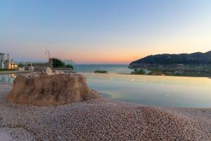 een grote rots zittend op een lichaam van water bij Hotel Residence Il Porto in Mattinata