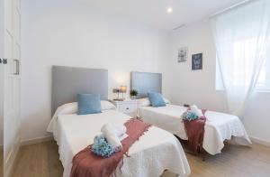 2 łóżka w białym pokoju z niebieskimi poduszkami w obiekcie Luxe Vista Histórico 5 rooms 4 baños w mieście Jerez de la Frontera