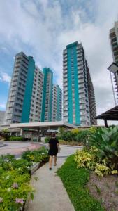 a woman walking down a sidewalk in front of tall buildings at The URBANSTAY Bacolod City in Bacolod