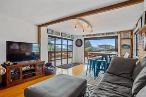 a living room with a couch and a tv and a table at Kiwiana Bach - Waihi Beach Holiday Home in Waihi Beach