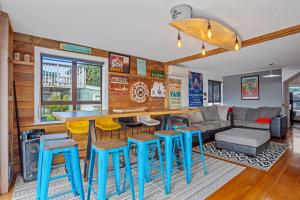 a kitchen and living room with a bar with blue stools at Kiwiana Bach - Waihi Beach Holiday Home in Waihi Beach