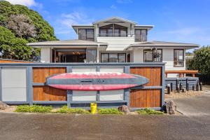 a house with a surfboard on top of it at Kiwiana Bach - Waihi Beach Holiday Home in Waihi Beach