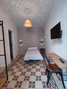 Zimmer mit einem Bett und einem Flachbild-TV in der Unterkunft Ibarra Hostel in Sevilla