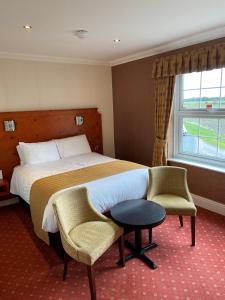 um quarto de hotel com uma cama e duas cadeiras e uma janela em Loftsome Bridge Hotel em Wressell