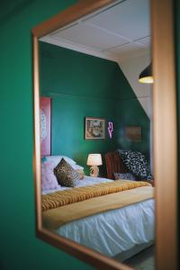 a mirror reflection of a bed in a green room at HARBOUR VIEW FUNKY AND ECLECTIC TWO BEDROOM HOME in Mossel Bay