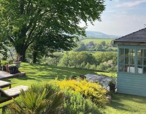 a garden with a bench and a building in the grass at Cargibbitt Annexe in Liskeard