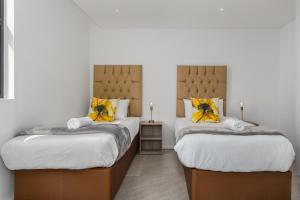 1 dormitorio con 2 camas con almohadas amarillas en The Iron Works Apartments en Ciudad del Cabo