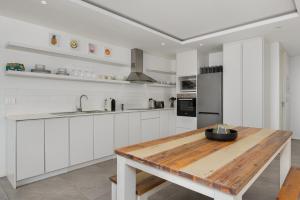 cocina con armarios blancos y mesa de madera en The Iron Works Apartments, en Ciudad del Cabo