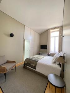 a bedroom with a bed and a chair and a television at BF 677 in Vila do Conde