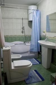 a bathroom with a toilet and a tub and a sink at The Grand Hotel in Semey