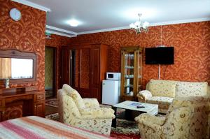 a living room with a couch and chairs and a television at The Grand Hotel in Semey