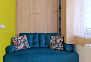 a blue couch with two pillows sitting in a room at Pokój 24E in Sobieszewo