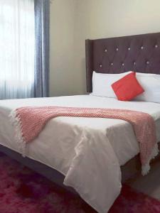 una camera da letto con un grande letto con cuscini rossi e bianchi di Comfy hidden home in Mthatha a Mthatha