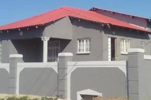 ウムタタにあるComfy hidden home in Mthathaの二つのガレージドアと赤い屋根の家