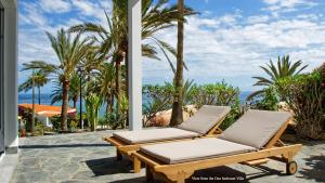two lounge chairs on a patio with palm trees and the ocean at Deva Beach Boutique Apartment in Maspalomas