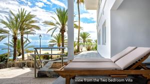 a porch with a bench and palm trees and the ocean at Deva Beach Boutique Apartment in Maspalomas