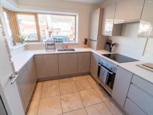 a kitchen with white cabinets and a sink and a window at Pass the Keys New 3bedroom house with free parking on premises in Nottingham