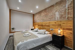 - une chambre avec un grand lit et un mur en briques dans l'établissement BBarcelona Dúplex Poble Sec, à Barcelone