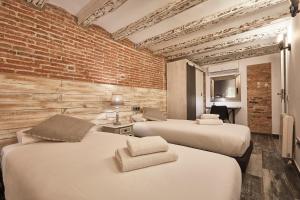 duas camas num quarto com uma parede de tijolos em BBarcelona Dúplex Poble Sec em Barcelona