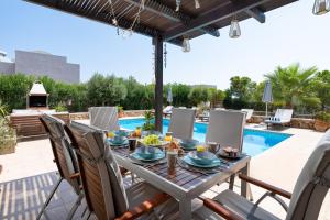 Un patio con mesa y sillas junto a una piscina. en Villa Paradeiso with Private Pool, en Lindos