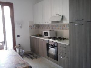 uma cozinha com armários brancos, um fogão e um micro-ondas em Da Antonio em Càbras