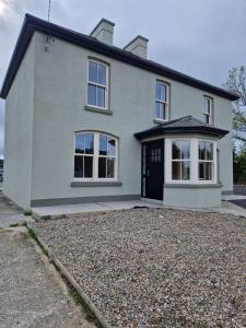 ein weißes Haus mit großer Kieseinfahrt in der Unterkunft Mountmahon House in Abbeyfeale