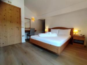 1 dormitorio con cama, escritorio y puerta en Hotel Grizzly, en Folgaria
