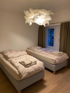 Habitación con 2 camas individuales y lámpara de araña. en Vöens, St-Blaise, Logement entier - 2 chambres, en Marin