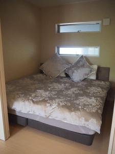una cama con almohadas y una ventana en una habitación en Harbour Inn & Suites 202, en Niigata