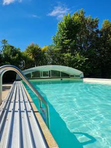 una piscina con un banco y un edificio en Gîte "Dans les Airs", avec piscine chauffée et parking, en La Roche-sur-Yon